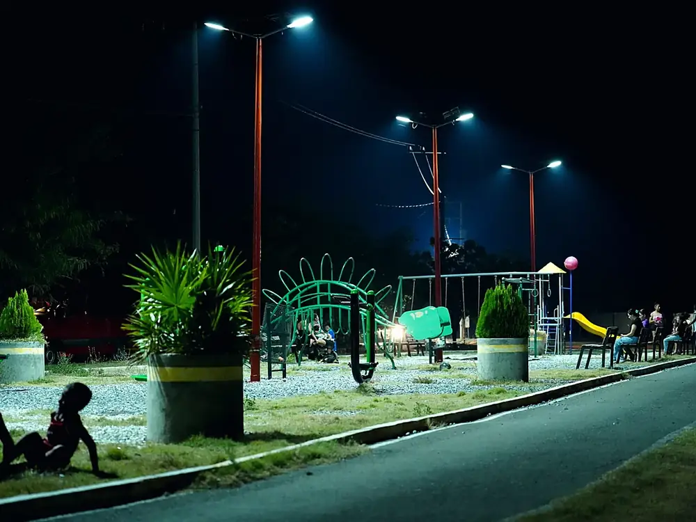 Familias y niños en el parque comunitario iluminado por las nuevas lámparas solares