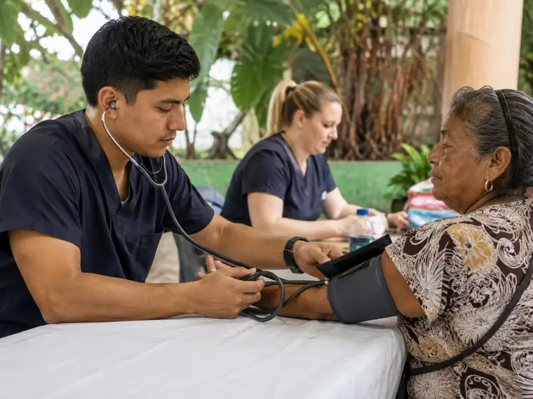 Personal voluntario tomando la presión a una mujer en una jornada de salud