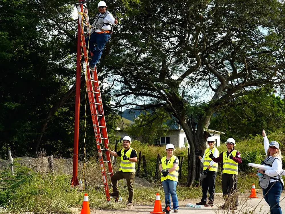 Técnico y voluntarios instalando una luminaria solar sobre un poste en La Blanca, Oaxaca