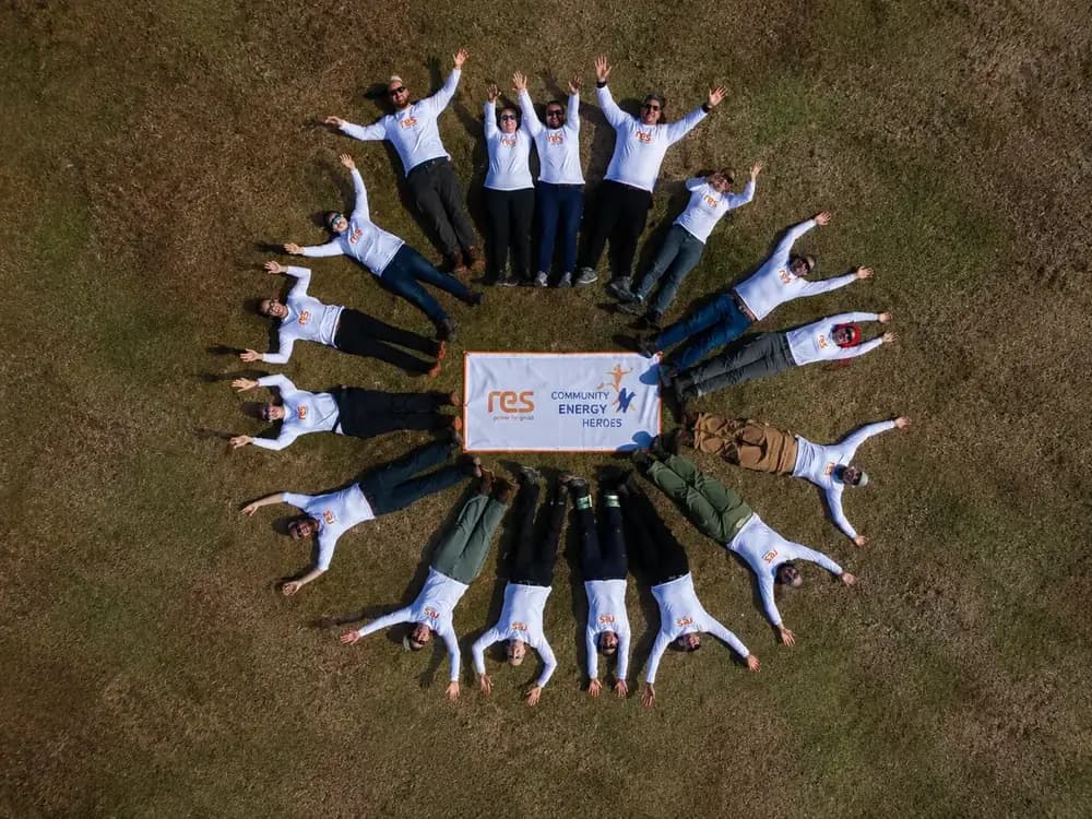 Vista aérea del equipo de voluntarios formando un círculo alrededor de la manta Community Energy Heroes