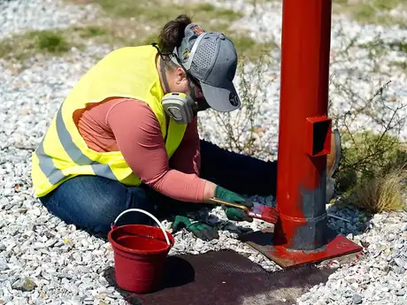 Voluntario aplicando pintura anticorrosiva a la base de un poste de alumbrado