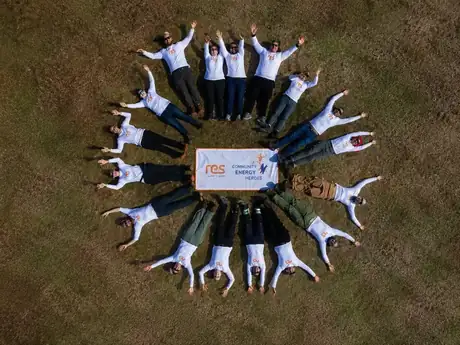 Vista aérea del equipo de voluntarios formando un círculo alrededor de la manta Community Energy Heroes
